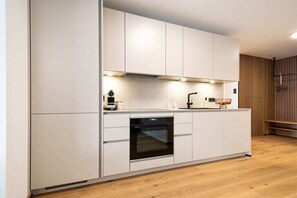 Eine moderne Küche mit weißen Schränken, einem eingebauten Ofen und Holzboden.
