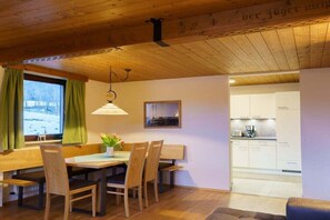A dining area with wooden furniture, a window with curtains, and a view of the outside. - in the Jagdhof apartment building (Reith bei Seefeld)