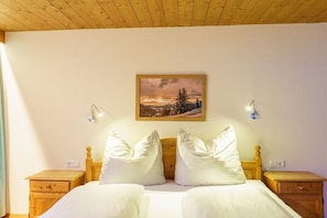 A bed with white bedding, two bedside tables, a wooden headboard, and a framed picture on the wall. - in the Jagdhof apartment building (Reith bei Seefeld)