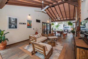 Una habitación amplia con techo de madera, un sofá, una mesita de centro y un área de comedor con mesa y sillas.