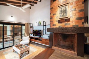 Una sala de estar moderna con chimenea, piso de madera, un sofá blanco y una televisión.