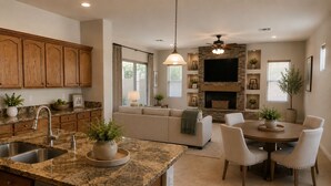 A spacious kitchen with granite countertops, a built-in dishwasher, wooden cabinets, and a dining area with a round table and chairs. - Charming 3 bed 3 bath gated community w/ office, large chefs kitchen & laundry (Chandler)