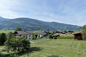 Ein ländliches Dorf mit Häusern, einem Feld und Bergen im Hintergrund.