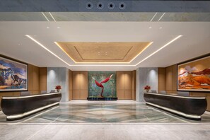 A spacious lobby with a reception desk, a large abstract painting, and a unique red sculpture. - Wyndham Garden Kashgar Tashkurgan (Taxkorgan Tajik)