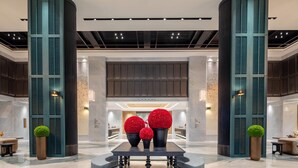 Eine Lobby mit einer Rezeption, einem Marmorboden und dekorativen roten Kugeln.