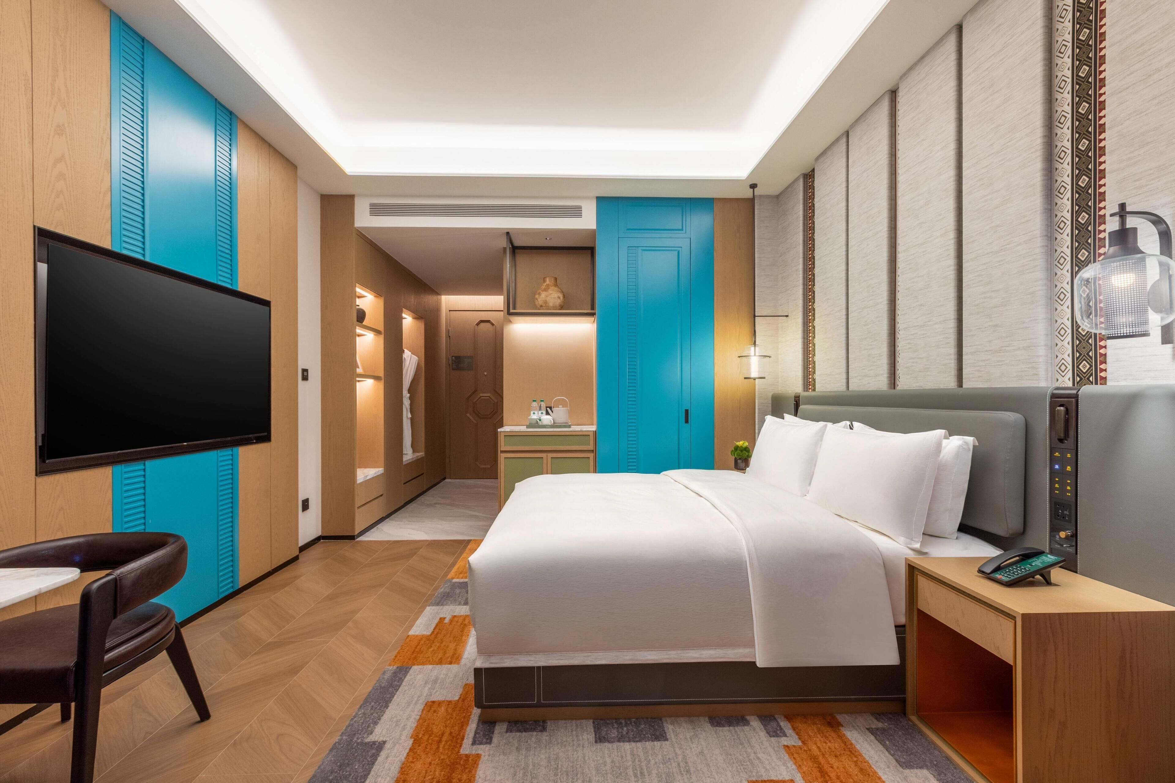 Une chambre d’hôtel comprenant un lit, un bureau, une chaise, une télévision et une salle de bain.