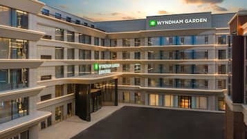 A multi-story hotel with a prominent 'WYNDHAM GARDEN' sign, featuring a modern architectural design with balconies and large windows.