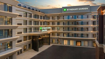 Um hotel com vários andares e um grande letreiro 'WYNDHAM GARDEN', com arquitetura moderna, varandas e amplas janelas.