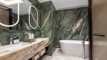 A modern bathroom with a marble vanity, a freestanding bathtub, and a large mirror with a light fixture.