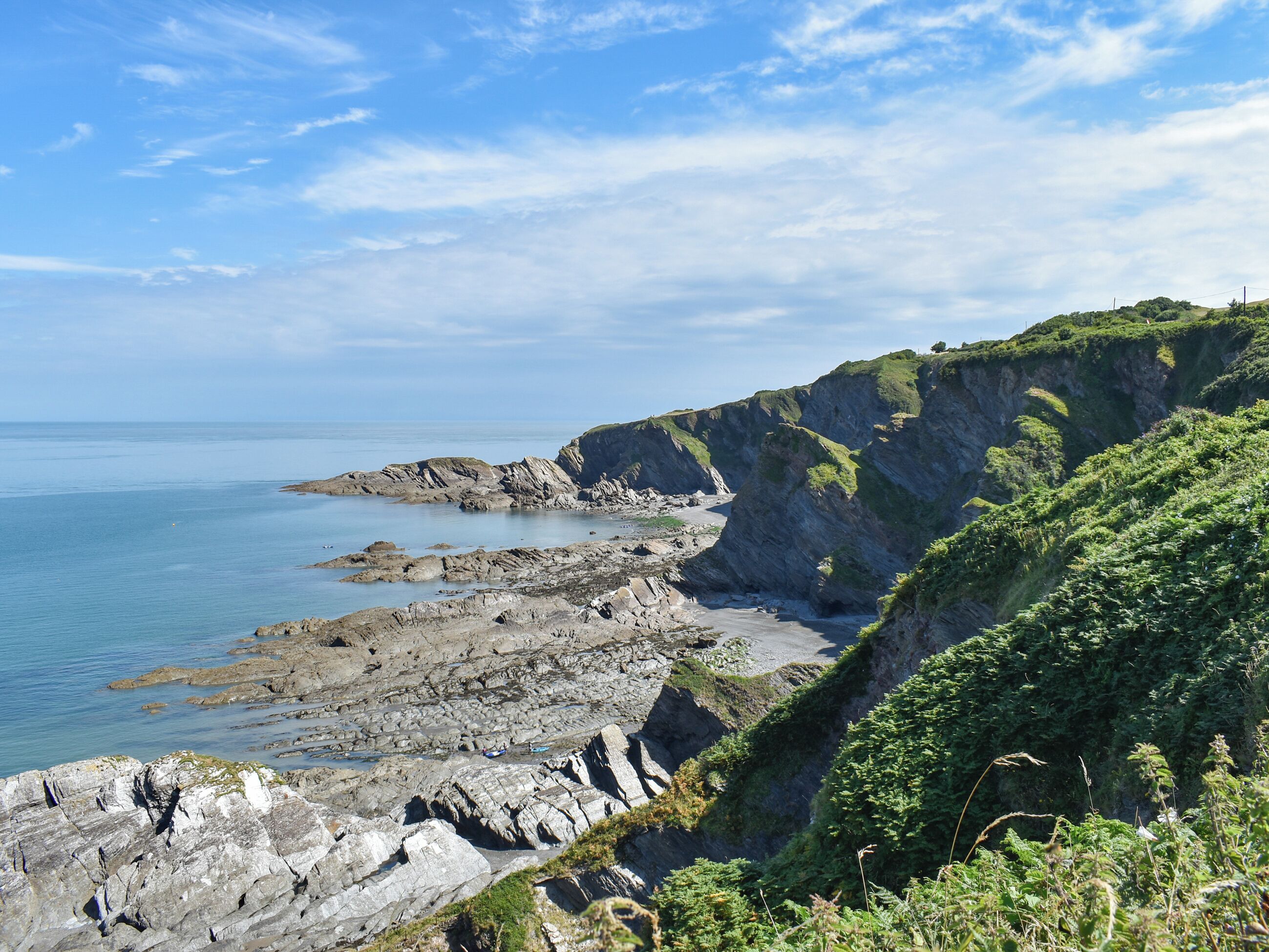 Un paysage côtier avec des falaises rocheuses, une plage et un ciel dégagé.