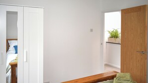 Een slaapkamer met een bed, een houten bankje en een groene handdoek.