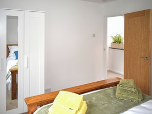 A bedroom with a bed, a wooden bench, and a green towel. - 1 bedroom accommodation in Combe Martin (Combe Martin)
