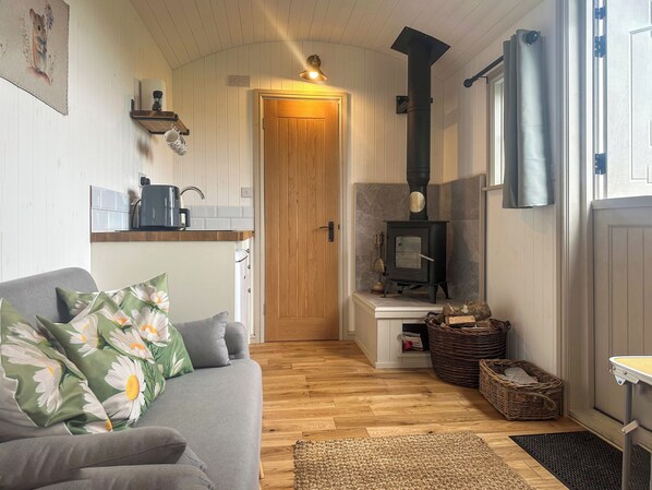 Ein gemütliches Wohnzimmer mit Sofa, Kamin, Küchenzeile und Holzboden.