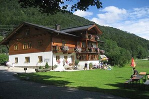 A wooden chalet with a balcony, a grassy lawn, and a mountain backdrop. - Sonnberg Groß - Haus Hirschpoint (Faistenau)
