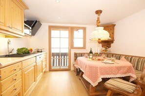 Eine Küche mit Holzausbau, einem Esstisch mit rosa Tischdecke und einer hölzernen Bank.