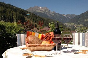 Ein Tisch mit einem Brotkorb und Weingläsern, vor einer Berglandschaft.