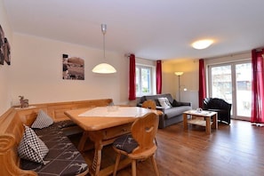 A living room with a wooden bench, a sofa, a dining table, and a coffee table. - Eberle Country House (Hirschegg\/Kleinwalsertal)