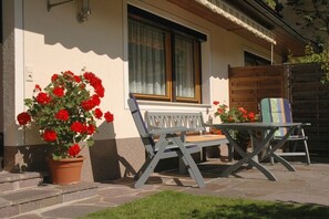 Eine Terrasse mit einer Bank, einem Tisch, einem Blumentopf und einem Holzzaun.