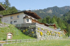 A traditional Alpine-style building with a stone facade, wooden balconies, and a sign indicating it is a guesthouse. - Ziller in the House Fernblick (Mayrhofen)
