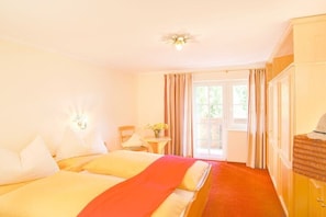 Ein Hotelzimmer mit zwei Betten, einem kleinen Tisch mit einer Vase, einem Sessel und einem Kleiderschrank.
