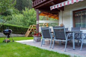 Eine Terrasse im Freien mit Grill, Stühlen und Tisch.