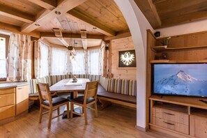 Ein Holzkamin mit einem Esstisch, Stühlen, einer Bank, einem Fernseher und einer Wanddekoration.