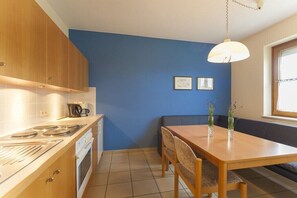 A compact kitchen with a dining area, a blue accent wall, and a window. - at the country house Luka (Mörbisch)