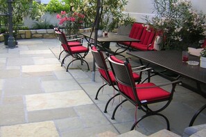 An outdoor patio with a table and chairs, stone flooring, and potted plants. - at the country house Luka (Mörbisch)