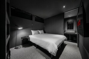 A modern hotel room with a large bed, bedside table, and a built-in vanity with a mirror. - THE DWBL HOTEL B (Otaru)