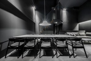 A modern dining area with a long table, multiple chairs, a pendant light, and a staircase in the background. - THE DWBL HOTEL B (Otaru)