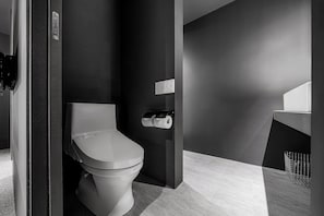 A modern bathroom with a toilet, a paper towel dispenser, and a sink. - THE DWBL HOTEL B (Otaru)