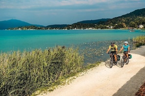 Ein Weg entlang eines Sees mit zwei Radfahrern.