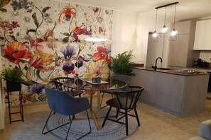 Eine moderne Küche mit einer zentralen Kochinsel, Pendelleuchten und blumengemustertem Wandpapier.