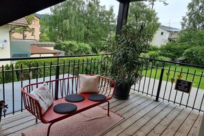 Ein Balkon mit einer roten Metallbank, einem Blumentopf und einem Schild in einer Fremdsprache.