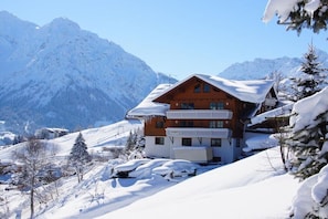 Eine Berglodge mit Holzhülle, mehreren Balkonen und verschneiter Landschaft.
