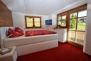 Ein Zimmer mit einem Bett, einem Fernseher, einem Fenster und einer Pflanze.