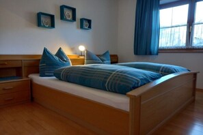 Ein Schlafzimmer mit einem hölzernen Bett, einem Nachttisch, Vorhängen und einem Fenster.