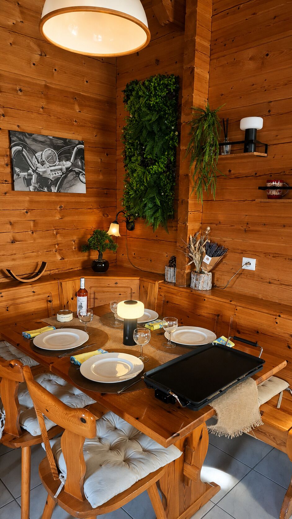 Un coin repas en bois avec une table dressée pour quatre personnes, comprenant des assiettes, des verres et des couverts.