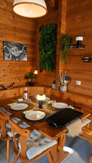 Un coin repas en bois avec une table dressée pour quatre personnes, comprenant des assiettes, des verres et des couverts.