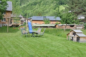 Ein rustikaler Außenbereich mit Tisch und Stühlen, einer Rutsche und einer kleinen Holzkonstruktion.