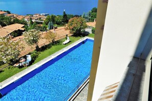 Ein Schwimmbecken mit Blick auf das Meer und umliegende Gebäude.