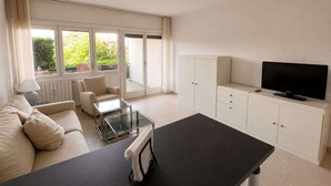 A modern living room with a sofa, coffee table, TV, and cabinets. - Lake View Apartment in Luino for 4 (Luino)