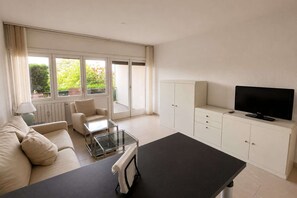 Ein modernes Wohnzimmer mit Sofa, Couchtisch, Fernseher und Schränken.