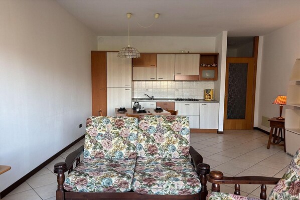 A living room with a sofa and a dining table, a kitchen with cabinets and a sink, and a door leading to another room. - Romantic Lake View Base in Germignaga (Germignaga (VA))