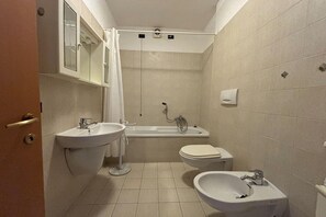 Kylpyhuone, jossa on pesuallas, bidee, wc ja kylpyamme.