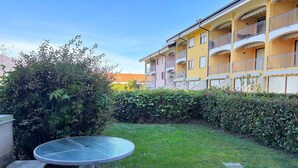 A courtyard with a round table, a hedge, and a yellow building with balconies. - Romantic Lake View Base in Germignaga (Germignaga (VA))