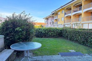 A courtyard with a round table, a hedge, and a yellow building with balconies. - Romantic Lake View Base in Germignaga (Germignaga (VA))