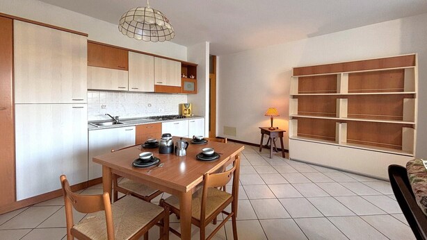 A modern kitchen with white cabinets, a dining table with chairs, a coffee maker, and a pendant light. - Romantic Lake View Base in Germignaga (Germignaga (VA))