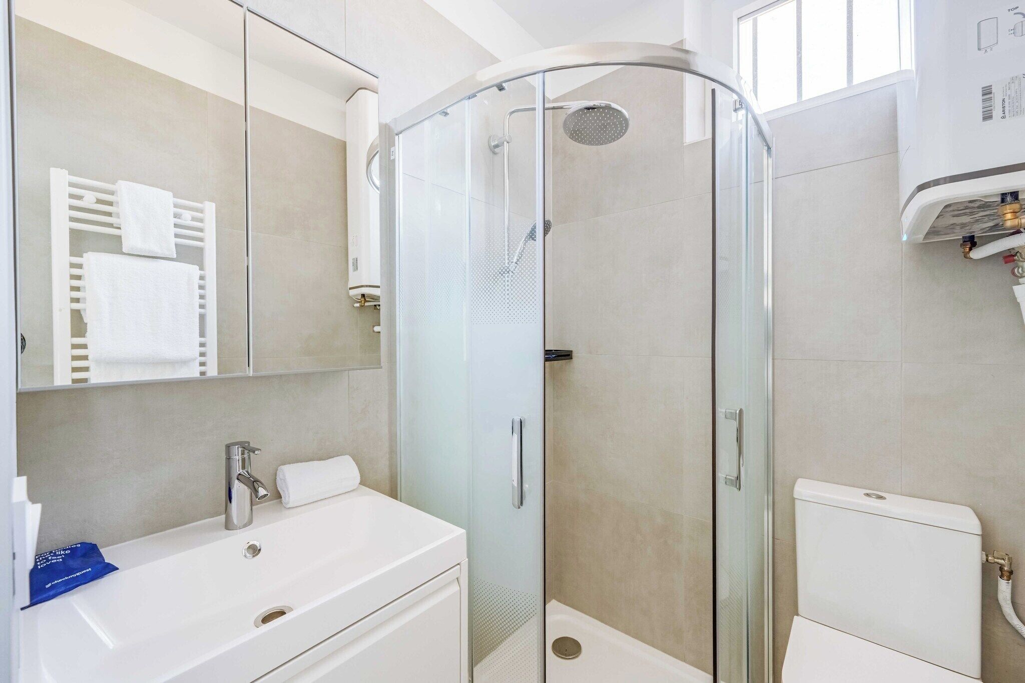 Un bany modern amb dutxa amb envàs de vidre, un lavabo blanc i un vàter.