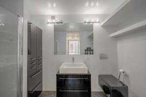 A modern bathroom with a large mirror, a white sink, and a glass shower enclosure. - 1BDR/4P Apt in the Heart of Saint-Tropez-near Port (Saint-Tropez)